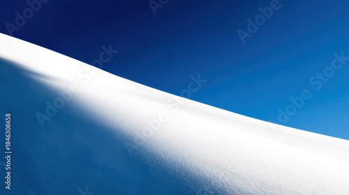 minimalist winter landscape presenting a sweeping white snowdrift curve against a vibrant deep blue sky creating a stark contrast and serene cold natural beauty