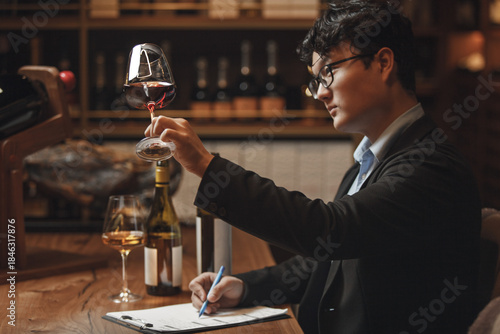 Slika na platnu Asian Ethnicity Professional Sommelier Tasting Red Wine in Wine Cellar, Close up Photo