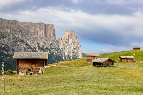 Mountain cabins in front of the peaks of the Schlern on the Seiser Alm, Dolomites, South Tyrol, Italy.