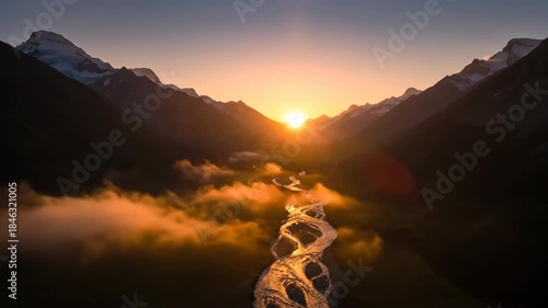 Scenic mountain valley with river flowing through the mist at sunrise