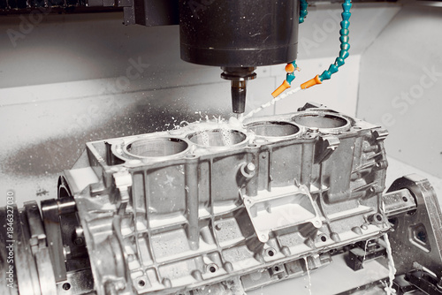 CNC milling machine grinds holes in car engine with coolant. Process of setting up engine cylinder blocks on a numerically controlled machine. 