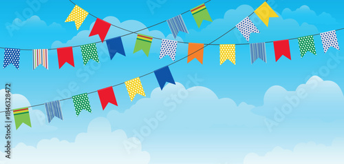 Colorful pennant flags strung across a bright blue sky with fluffy white clouds create a festive atmosphere