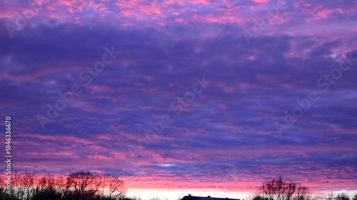 Vibrant Purple and Pink Cloudy Sunset Sky Over Quiet Suburban Horizon