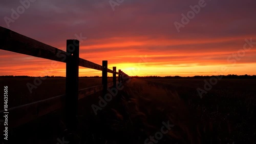 Rural fence at dawn with golden light and glowing, colorful sky