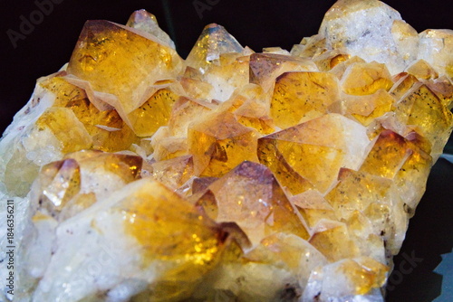 Tableau sur toile Macro photo of a golden yellow citrine quartz crystal cluster on a dark background, highlighting natural facets and sparkling texture