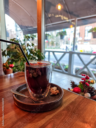 Close-up of mulled wine in a glass cup with cinnamon stick, cloves and orange slices. Traditional hot spiced red wine, cozy winter drink served in a café, perfect for Christmas and holiday atmosphere.