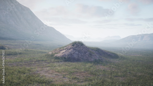 Foto A tranquil valley stretches beneath distant mountains, with a small grassy mound in the center