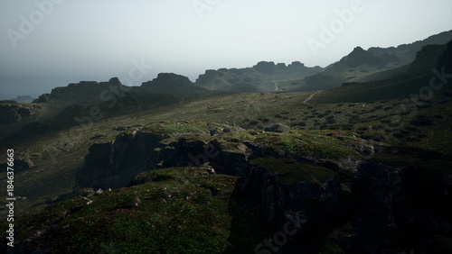 Sunset casts a soft glow over rugged hills by the coast. The landscape reveals rocky cliffs, lush green patches, and winding paths that lead to the endless horizon over the ocean.