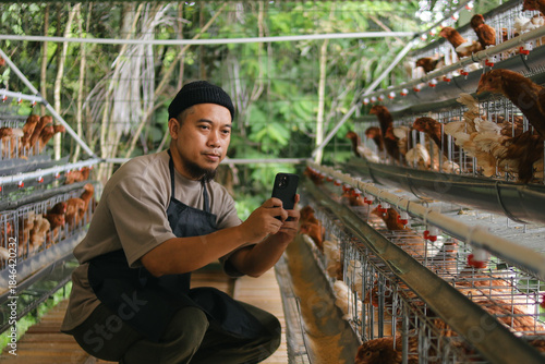 Modern Farmer Uses Smartphone to Check on His Chickens in Professional Poultry Farm