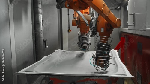 Industrial robotic arms perform automated high-pressure waterjet cutting of a car body panel inside a manufacturing cell. Precision waterjet technology enables accurate