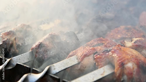 Close-up of juicy meat fried on fire, meat in smoke. Shish kebab on skewers is cooked over hot coals. The concept of cooking meat on the grill.