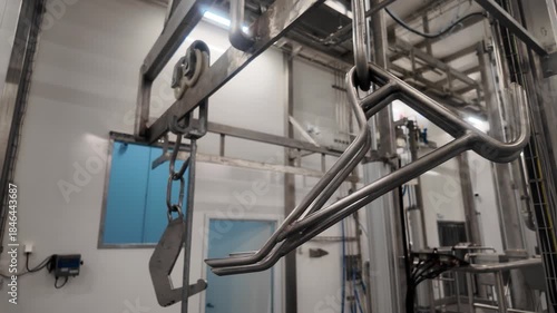 Industrial stainless steel overhead rai, conveyor system with hooks and shackles inside a clean meat processing facility or slaughter house .