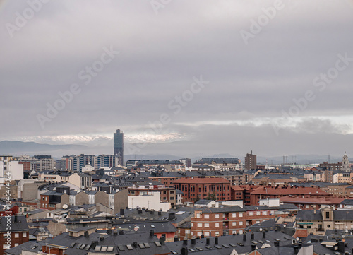 View of the city of Ponferrada and the large radio tower standing out among the buildings and the mountains of El Bierzo covered in snow and fog in the background