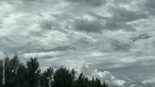 Thick gray clouds fill most of the frame, with treetops visible along the lower edge.