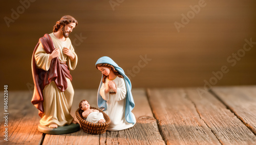 Nativity scene figurines of Mary Joseph and baby Jesus on wooden background.
