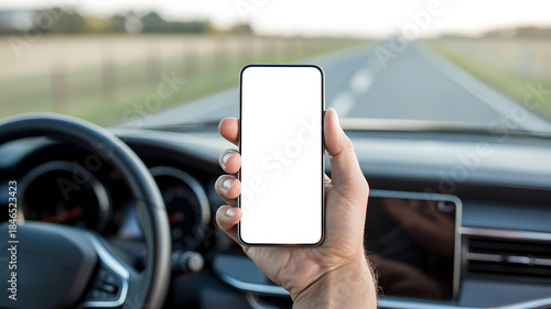 Hand holding a smartphone with blank screen inside a car on a road