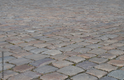 Background of cobblestones photographed from the side. A large square is covered with cobblestones.