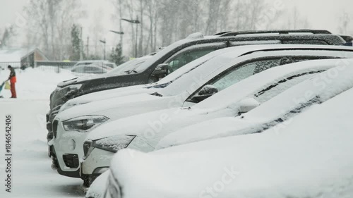 Snow falling against a backdrop of parked cars 
