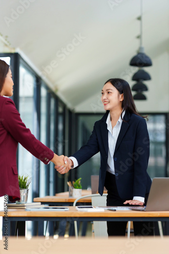 Two smiling businesswomen shaking hands agreeing on a partnership, symbolizing successful collaboration and an important business deal