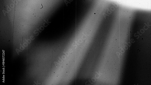 Abstract monochrome background featuring grainy texture, dust particles, scratches, and subtle light variations in black and white tones. Aged analog aesthetics create a gritty, distressed atmosphere 