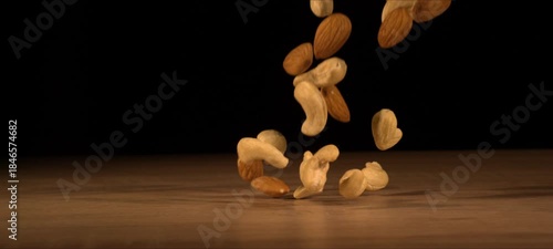 Wallpaper Mural Super slow-motion of almonds and cashews fall on wooden table. Healthy snack, satisfying crunch. Torontodigital.ca