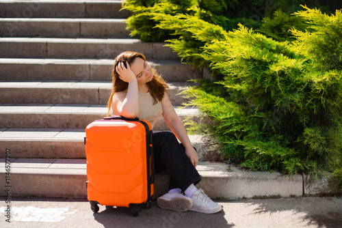 woman hands holding orange suitcase standing on stairs outdoors to hotel