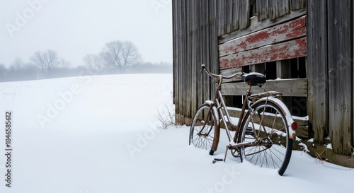 Old rusty bicycle covered in snow leans against a weathered barn.