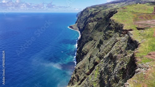 Aerial 4K drone footage of dramatic coastal cliffs and lighthouse viewpoint on Madeira island, overlooking the deep blue Atlantic Ocean and rugged shoreline in clear daylight.
