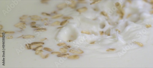 Slow motion oatmeal flakes falling into milk. Breakfast, healthy food, calm ASMR style