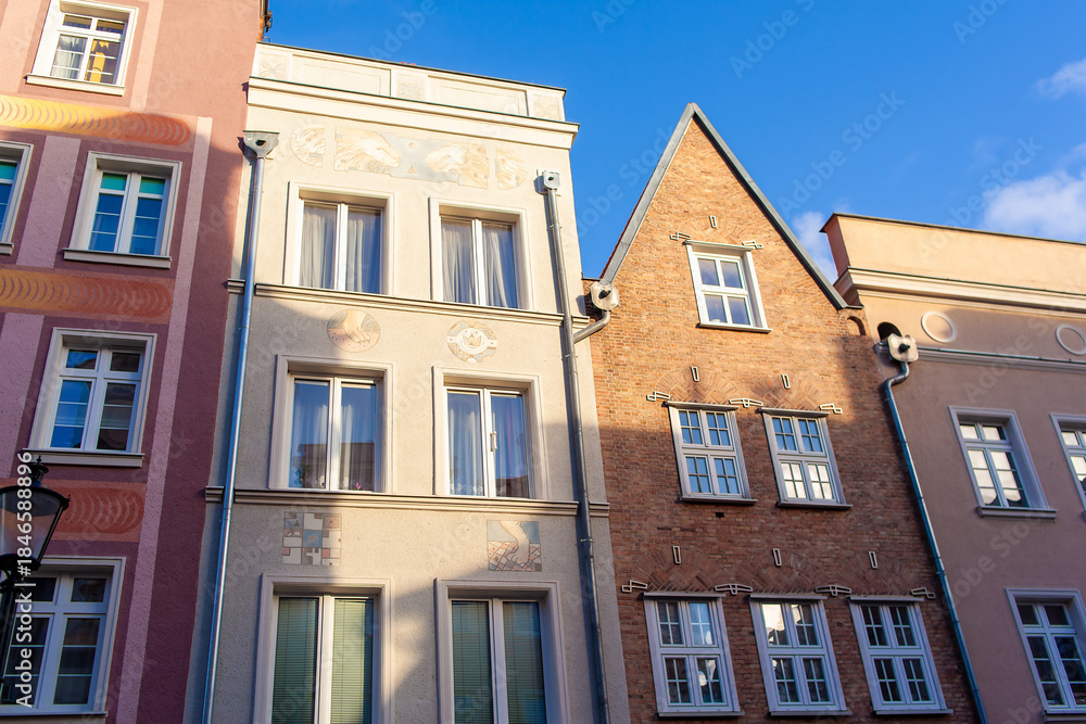 Fototapeta premium Distinct buildings share a street, showcasing diverse architectural styles and colors under bright sunlight in Gdansk, Poland