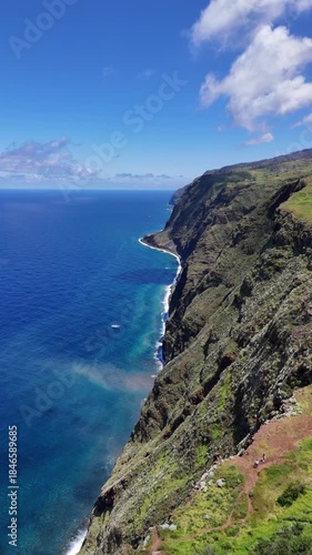 Aerial 4K drone footage of dramatic coastal cliffs and lighthouse viewpoint on Madeira island, overlooking the deep blue Atlantic Ocean and rugged shoreline in clear daylight.