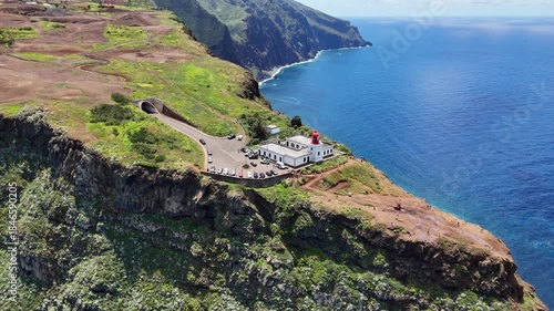 Aerial 4K drone footage of dramatic coastal cliffs and lighthouse viewpoint on Madeira island, overlooking the deep blue Atlantic Ocean and rugged shoreline in clear daylight.