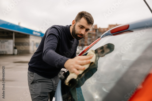 Young man washing car as part of auto maintenance