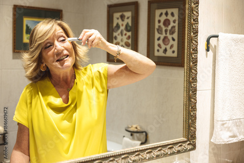 Senior woman enjoying her skincare routine with a facial device in the bathroom