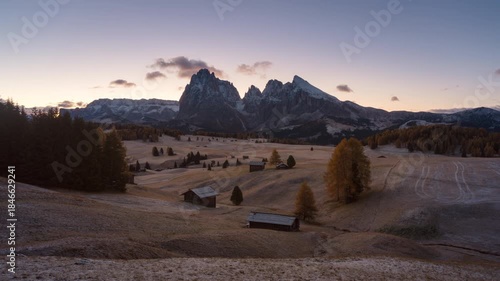 Alpine landscape of sunrise over Alpe di Siusi with wooden huts and autumn grass hill in Dolomites, Italy