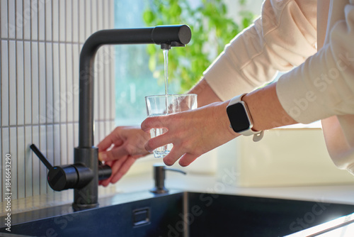 Wallpaper Mural Hand filling glass with drinking water from kitchen faucet in modern home interior. Woman pouring clear water from tap filter. Concept of drinking water, daily hydration and quenching thirst Torontodigital.ca