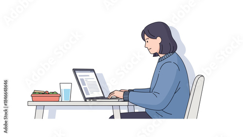 Young woman working on a laptop at a desk with a meal and drink nearby in a simple modern workspace
