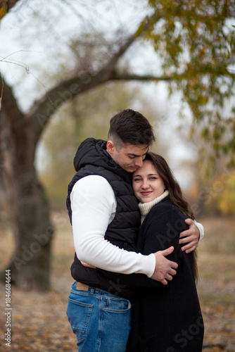 A young man and woman hugging sweetly in an autumn park