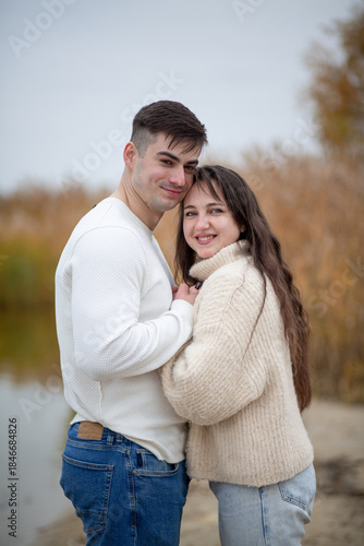 A happy young couple is walking on the river bank