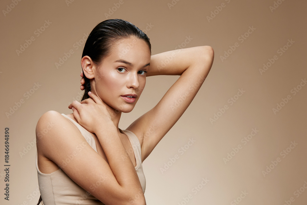 Obraz premium Young woman with natural beauty posing against a soft brown background, showcasing healthy skin and effortless style Perfect for beauty and skincare themes