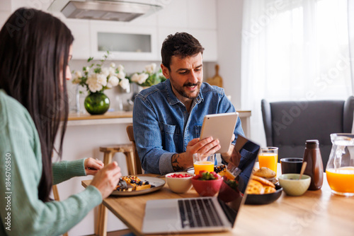 Wallpaper Mural Couple using laptop and tablet computers while having breakfast at home Torontodigital.ca