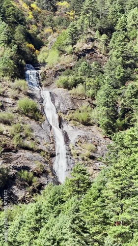 Majestic view of the green mountains valley and waterfall, vertical nature background, green valley under the mountains.