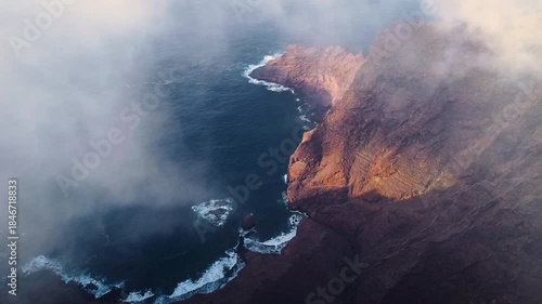 Aerial drone view of the volcanic cliffs in northern Tenerife, Anaga area, overlooking the Atlantic Ocean with coastal mist and a wild natural landscape, ideal for travel and nature tourism. 