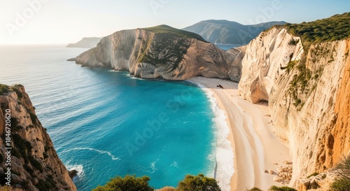Golden sun illuminates towering cliffs above a turquoise beach