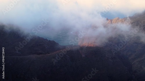 Aerial drone view of the volcanic cliffs in northern Tenerife, Anaga area, overlooking the Atlantic Ocean with coastal mist and a wild natural landscape, ideal for travel and nature tourism. 
