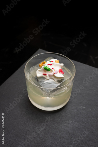 A refreshing beverage with colorful garnish in a glass. This drink is an artistic creation with ice cubes, adding to the refreshing experience