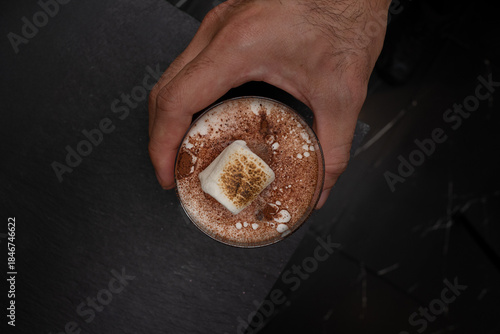 A delicious coffee drink with marshmallows, held by a hand