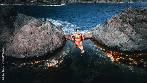 Young woman relaxing in the natural lava rock pools of Seixal on Madeira Island, Portugal