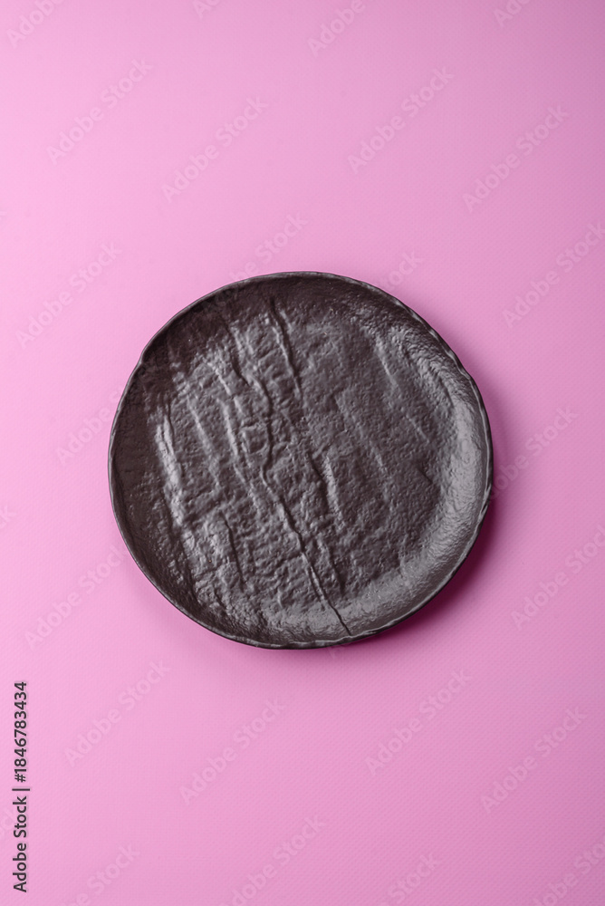 Naklejka premium An empty round ceramic plate on a pink background as a kitchen utensil. An empty plate