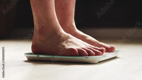 Close-up of male feet on a digital bathroom scale on a wooden floor.